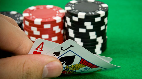 fingers holding cards with red and black chips on green table