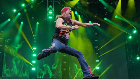 Bret Michaels jumping on a green stage