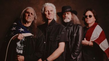 Four men holding american flag in front of a brown background, grand funk railroad band