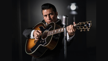 Johnny cash tribute with a guitar and microphone on a black backdrop