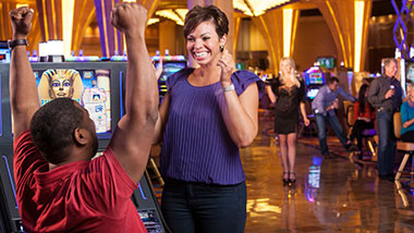 two people cheering at slot machine wide shot