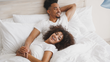 two people enjoying the comfort of the white sheets and bedding